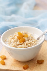 Porridge with raisin and honey in white bowl for breakfast