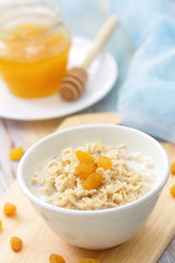 Porridge with raisin and honey in white bowl for breakfast