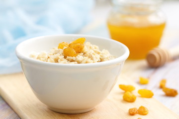 Porridge with raisin and honey in white bowl for breakfast