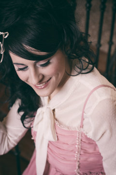 chica joven vestida con ropa de &eacute;poca en tonos pastel, sonriendo y con un gesto dulce 