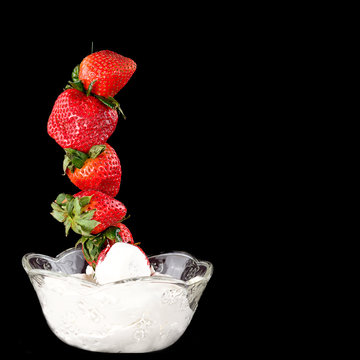 Black Background With A Bowl Of Whipped Cream And Strawberries Stacked High Out Of Them.  Concept Image