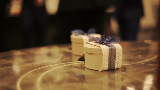 Little present boxes decorated with blue ribbons stand on the wooden table