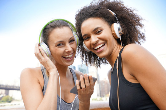 Girlfriends listening to music with smartphone while exercising