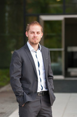 Standing businessman in suit in front of office park. man in suit in front of entrance door