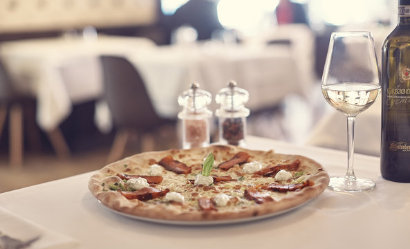 Fresh Pizza With Salmon And Mozzarella On The Background In A Local Shop Pizzeria With A Glass Of White Wine In A Restaurant