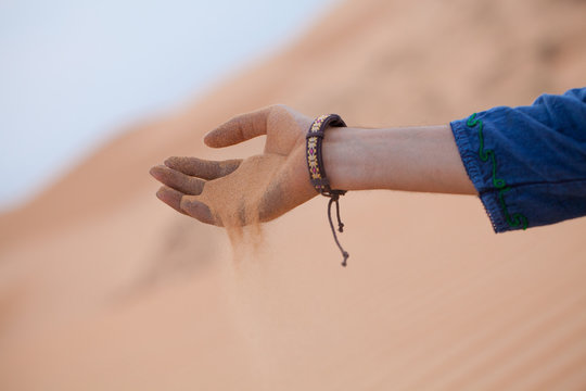Single hand holding sand in desert let it running through fingers, Muine sand dunes, Vietna