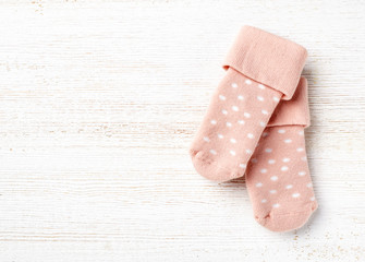 Pink baby socks on white wooden background
