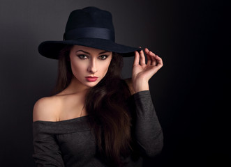 Fototapeta na wymiar Elegant makeup woman in fashion hat posing on dark shadow backgr