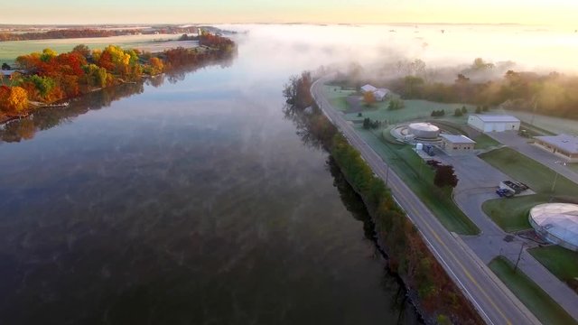 Sunrise over steaming, foggy autumn river, Fall colors adorning shore, aerial view.
