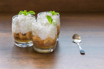 three banoffee pie in a cup.banoffee decorated with mint leaves placed in a wooden floor