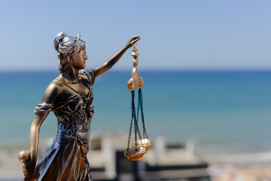 Sculpture of justice or themis goddess on outdoors bright blue sky background