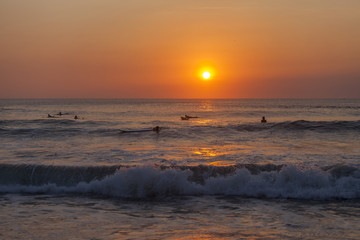 Silhouettes of surfers at the sunset at the Kuta beach, Bali, Indonesia