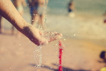 Hand and water, wet sand blurry outdoors background, close up image