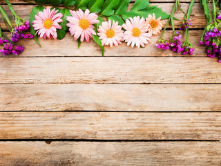 On a wooden texture arranged flowers and leaves.