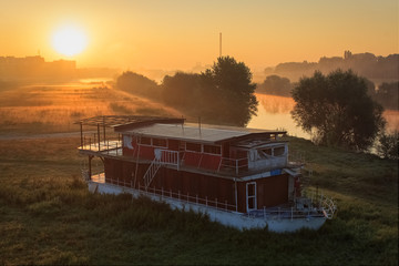 An old boat at sunrise by the river Sava under the Bridge of Liberty in Zagreb, Croatia, Europe