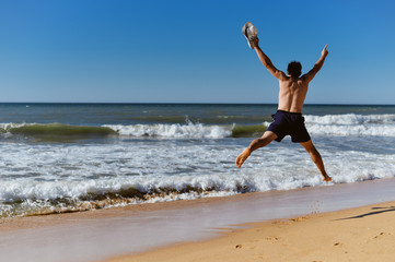 Fototapeta na wymiar Back view of joyful man on the beach sunny blue sky outdoors background