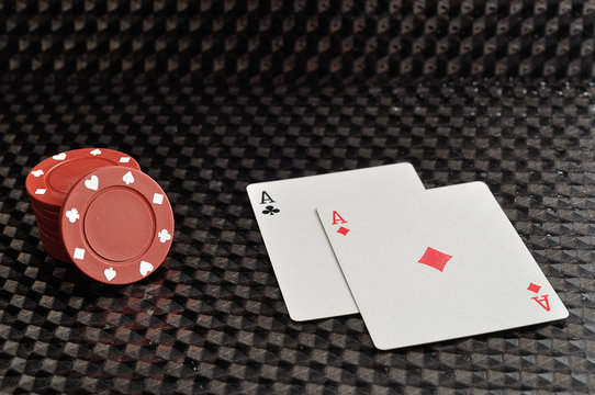 Two cards with red poker chips on a black background