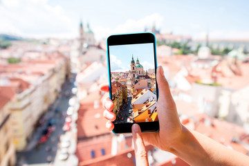 Holding a smart phone with photo of the lesser town with saint Nicholas church in Prague city