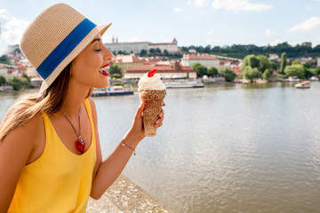 Young female tourist with traditional czech dessert called trdelnik on Charles bridge in Prague