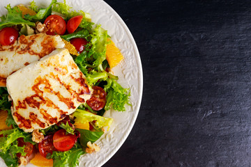 Grilled Halloumi Cheese salad witch orange, tomatoes and lettuce. healthy food