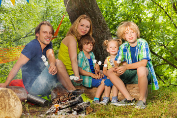 Happy family having rest and roasting marshmallow