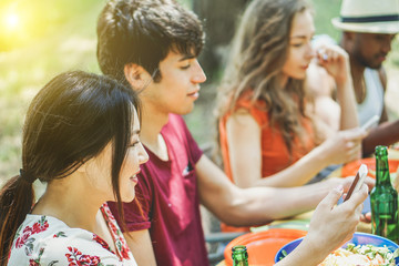 Group of multiracial students using their smartphone at barbecue meal