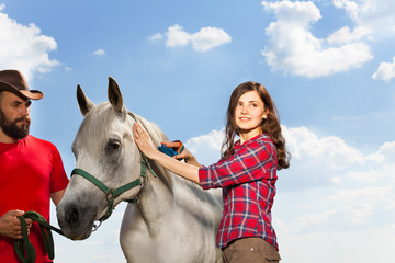Fototapeta premium Portrait of pretty woman brushing her white horse