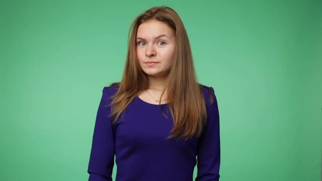 Young woman in a dark blue shirt is puzzled, chroma key green screen background