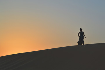 Fototapeta na wymiar girl in the setting sun in the desert