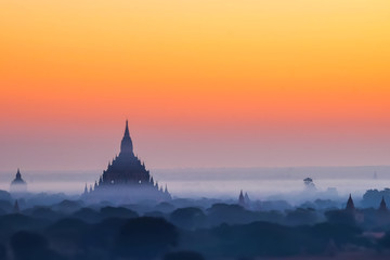 Fototapeta na wymiar Tilt Shift blur effect. Amazing misty sunrise colors and silhouette of ancient Myauk Guni Pagoda. Architecture of ancient Buddhist Temples at Bagan Kingdom. Myanmar (Burma) travel destinations