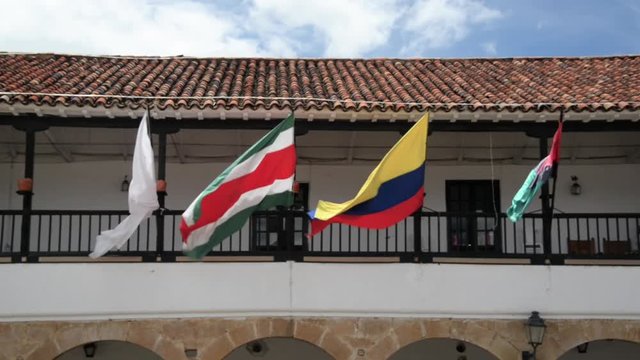Colombian and other flags blowing in the wind on a balcony in Villa de Leyva, Colombia