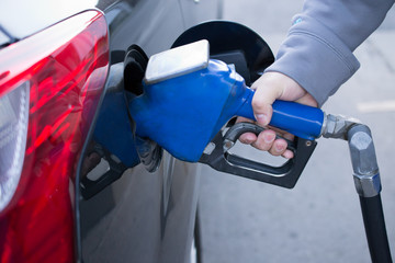 Pumping gas at gas pump. Closeup of man pumping gasoline fuel in