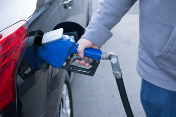 Pumping gas at gas pump. Closeup of man pumping gasoline fuel in