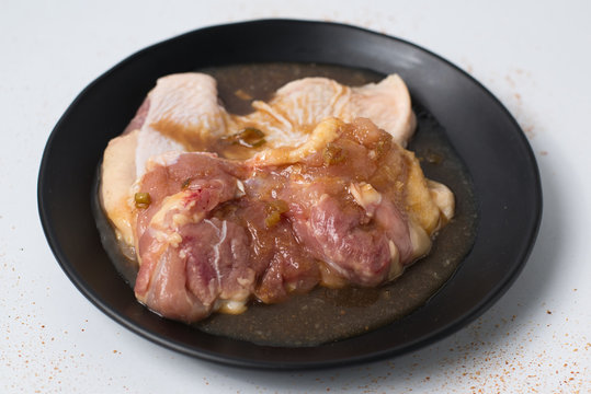 Fresh raw chicken meat seasoned with honey and sauce on black di