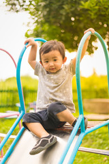 Fototapeta na wymiar Little Asian kid playing slide at the playground