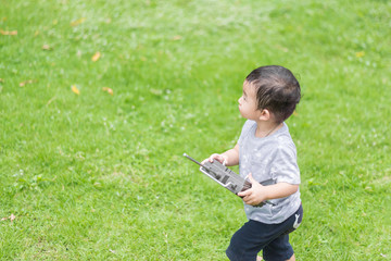 Little Asian kid holding a radio remote control (controlling han