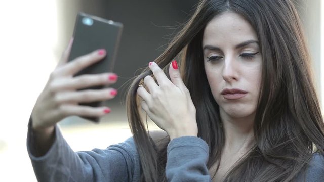 Young lady fixing her hair for better selfie