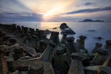 Seascape during sunrise  . Concrete block dropped as the waves silly beach at sunrise Beautiful natural summer seascape photo in beach Thailand . Long Exposure seascape photography .