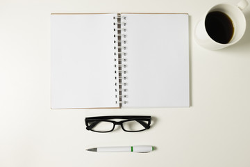 Top view  white desk with leye glasses, smart phone, pen  note b