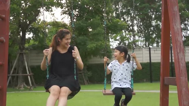 Asian mother and child play swing playground