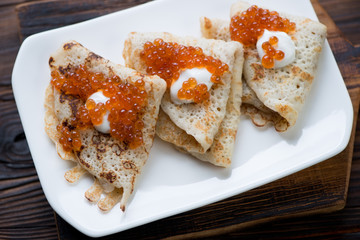 Close-up of crepes with red caviar, selective focus, studio shot