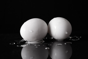 White Eggs isolated on black background with water drop and reflection.