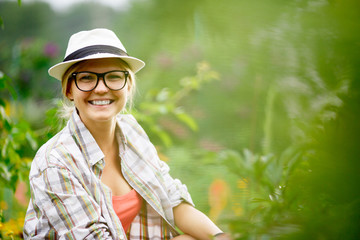 Young caucasian smiling woman caring for plants in her garden