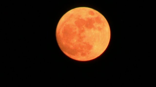 Orange full moon over dark sky