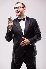 Naklejka premium Young man in suit singing over the microphone with energy. Isolated on white background. Singer concept.