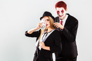 a young beautiful lady croupier and boy with an artistic make up joker . Gamble and casino concept. Studio shot. White background
