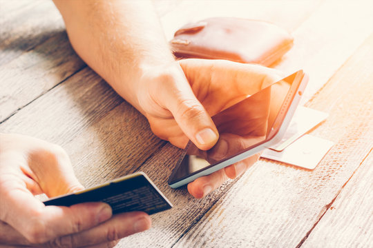 Man Hands holding credit card and using mobile phone in sunlight. Online shopping, online banking and online marketing. shallow depth of field, toning photo