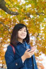 Happy young woman talking on mobile phone stand on autumn park