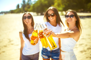Three beautiful young girls having fun on the beach and drink beer. Girls with bottles in their hands and rejoice. enjoy summer time. Fun at the beach. Great summer mood. sunny day