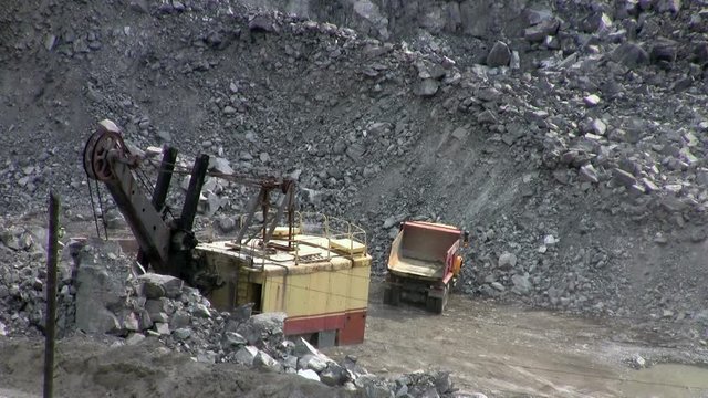 Machines excavate soil in an open pit
